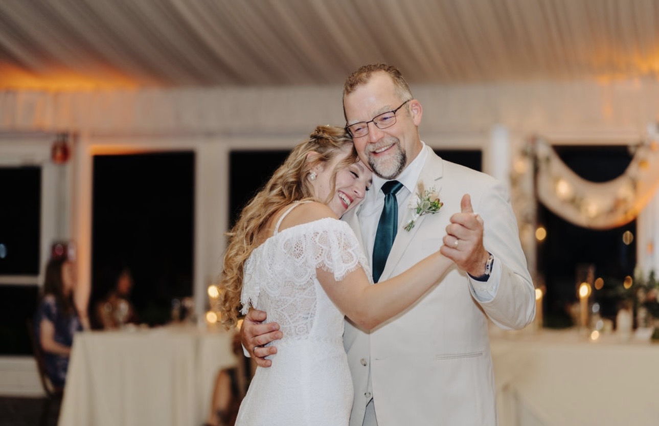 Professional event photography of a bride and her father sharing a sentimental first dance at a wedding reception.